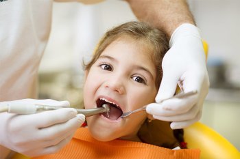 Dentist examining a young child's teeth during a pediatric dental visit in Millersville, MD