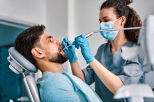 Dentist performing a teeth cleaning procedure on a patient, using dental tools in Millersville, MD